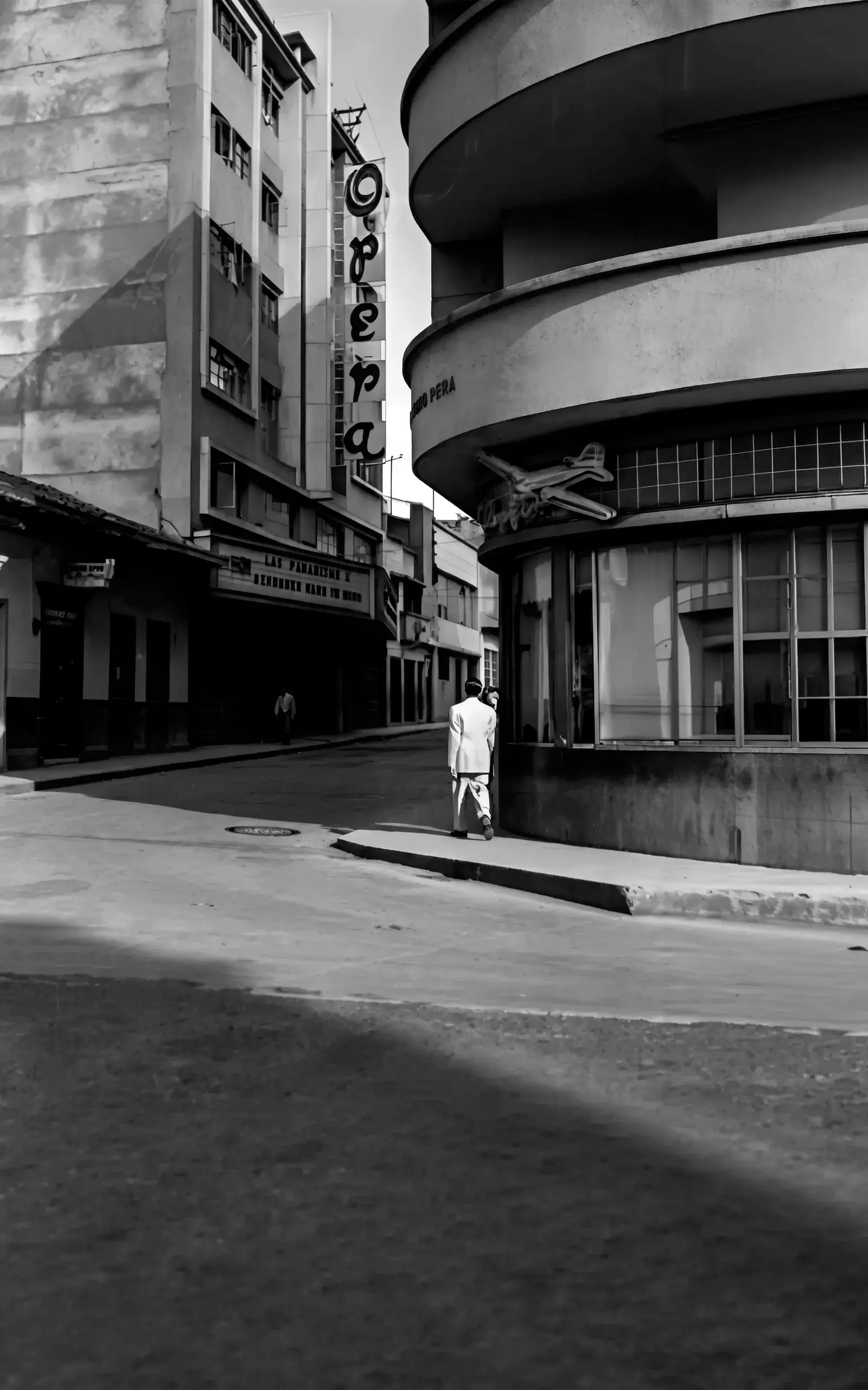 El teatro Ópera, identificado por su letrero vertical, y la fachada curva del edificio situado enfrente.
